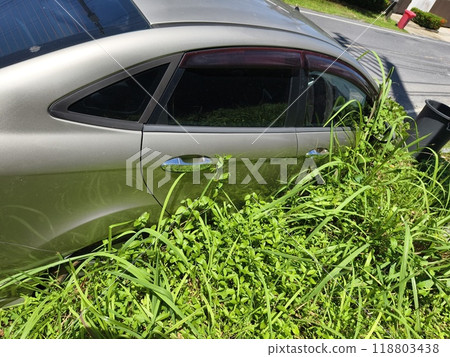 A silver car that has a broken tire and is covered with leaves 118803438
