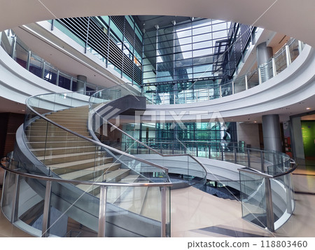 A beautifully designed spiral staircase in a modern building with glass railing 118803460