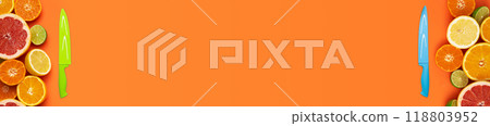 Flat layout banner with various fresh cut citrus fruits and one knife each on left and right side of image on orange background 118803952