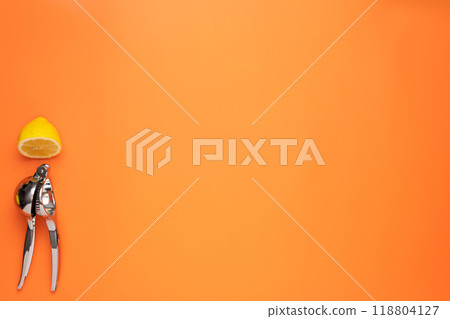 Half freshly sliced lemon lies together with lemon squeezer on orange background Half freshly sliced lemon lies together with lemon squeezer on orange background 118804127