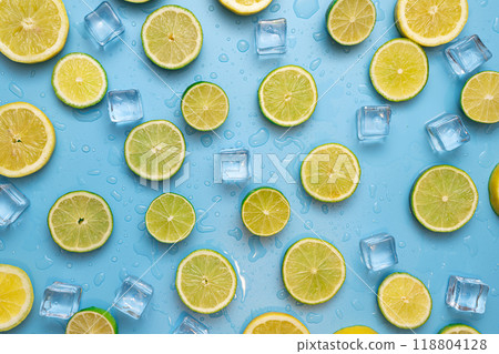 Delicious fruit background made of fresh sliced lemon and lime fruits on a blue background with ice cubes and waterdrops Delicious fruit background made of fresh sliced lemon and lime fruits on a blue background with ice cubes and waterdrops 118804128