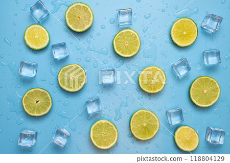 Delicious fruit background made of fresh sliced lemon and lime fruits on a blue background with ice cubes and waterdrops Delicious fruit background made of fresh sliced lemon and lime fruits on a blue background with ice cubes and waterdrops 118804129