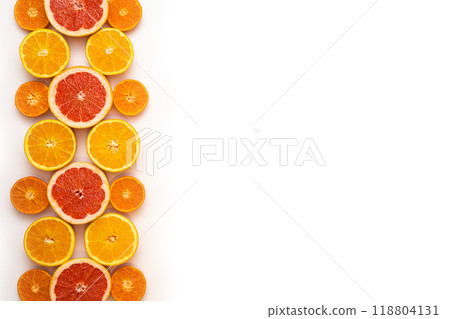 Fresh sliced and halved citrus fruits as a pattern in the left third of the image on a white background. 118804131
