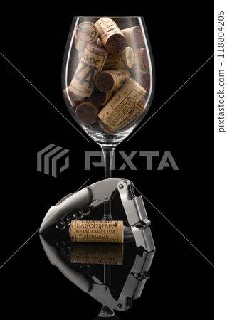 A wine glass filled with wine corks stands together with a fine metal wine set in front of a black background A wine glass filled with wine corks stands together with a fine metal wine set in front of a black background 118804205