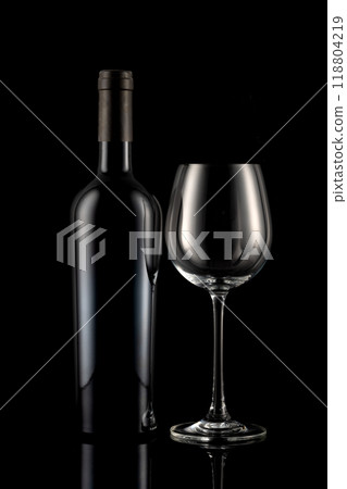 Wine bottle and wine glass in front of a black backgound 118804219