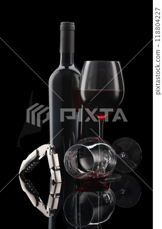 Glass of red wine with bottle and wine cutlery in front of black background 118804227