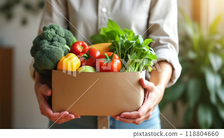 Woman holding a cardboard box of fresh organic vegetables 118804660