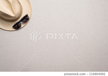 Summer, beach and vacation concept with free text space. Top view. Flat layout with a man straw hat and sun glasses in the upper left corner on a fine sandy background 118804892