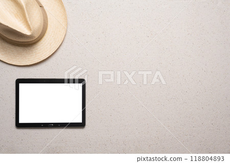 Summer, beach and vacation concept with free text space. Top view. Flat layout with a man straw hat in the upper left corner on a fine sandy background and a blank tablet with free text area in the 118804893