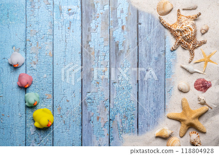 Summer, beach and vacation concept with free text space. Top view. Flat layout with a small group of colorful rubber ducks, large sea star and sea shell and various sea shells and fine beach sand on 118804928