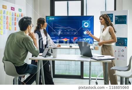 asian worman leader presenting a financial data and strategies in a modern office with charts and graphs displayed on a large screen 118805060