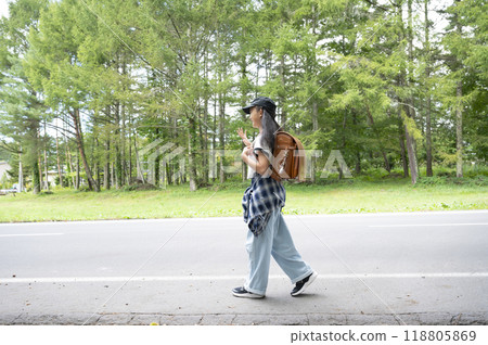 A girl in elementary school walking through the woods on her way to school in the countryside, carrying a backpack 118805869