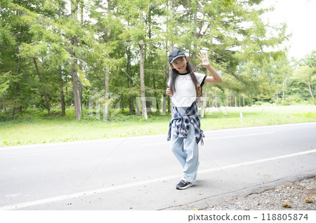 A girl in elementary school walking through the woods on her way to school in the countryside, carrying a backpack 118805874