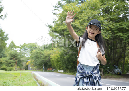 A girl in elementary school walking through the woods on her way to school in the countryside, carrying a backpack 118805877