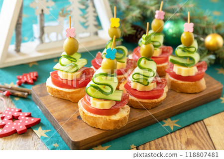 Creative appetizers christmas. Canapes Christmas tree of salami, cheese, olives, tomatoes and cucumbers with baguette on a rustic table. 118807481