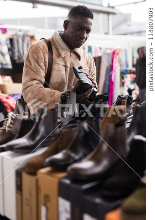 Man looks at new shoes at a flea market 118807903