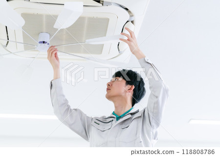 Male staff member performing air conditioner maintenance Male staff member performing air conditioner maintenance 118808786