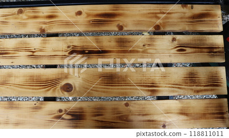 textured background of separate stained wooden planks with natural pattern on gray gravel background, fragment of bench made of wood with processed boards in structure 118811011