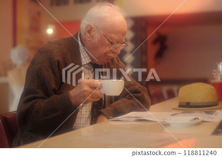 Elderly Man Drinking Coffee While Reading Newspaper 118811240