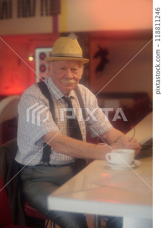 Portrait of Elderly Man Wearing Hat in Cozy Cafe Setting 118811246