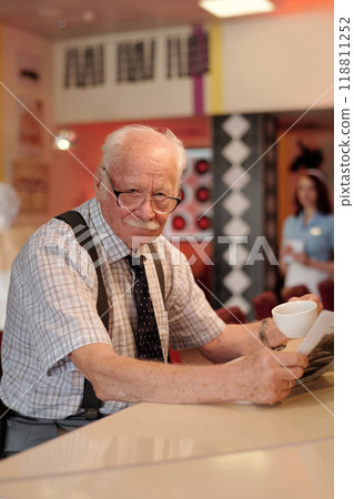 Engaging Elderly Man Enjoying Coffee at Cozy Cafe Counter Engaging Elderly Man Enjoying Coffee at Cozy Cafe Counter 118811252