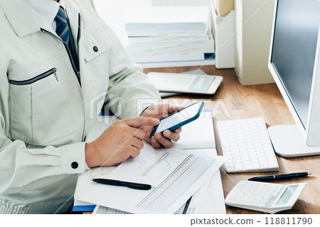 Man in work clothes operating a smartphone 118811790