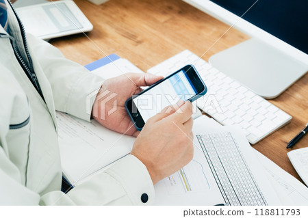 Man in work clothes operating a smartphone 118811793