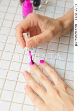 woman paints nails at home, manicures takes care of hands. bright pink nail polish woman paints nails at home, manicures takes care of hands. bright pink nail polish 118812281