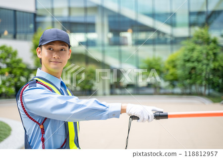A male security guard directing traffic with a guide stick 118812957