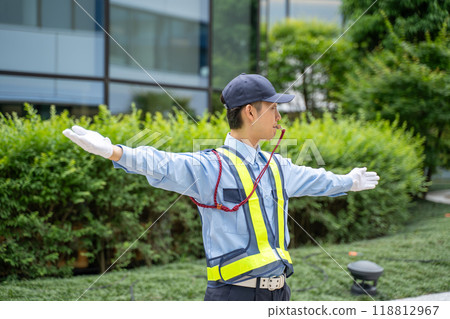 A male security guard directing traffic with a whistle signal 118812967