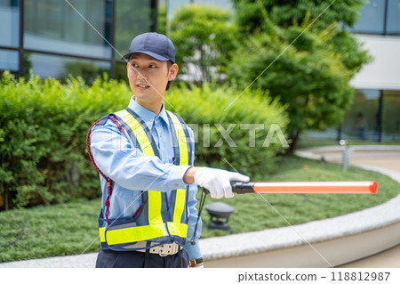 A male security guard directing traffic with a guide stick 118812987