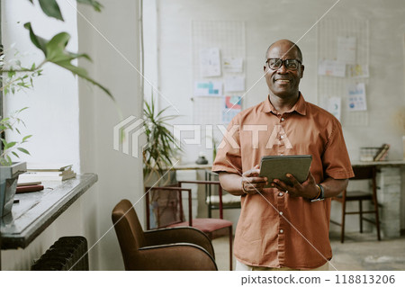 Portrait of smiling African American businessman posing for portrait and holding tablet in hands 118813206