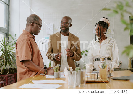 Serious African American boss having meeting with his subordinates in modern light office 118813241