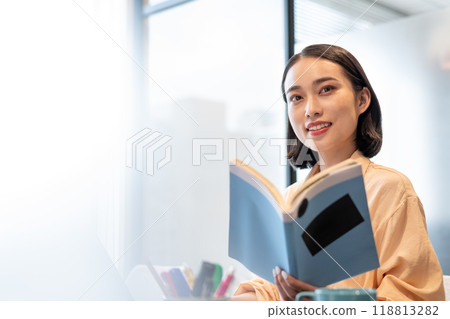 A woman smiling and looking at a reference book 118813282