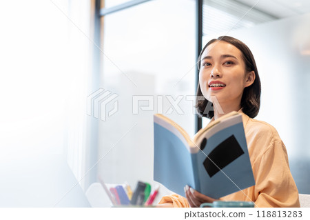 一位女士一手拿著參考書，微笑著看著這一幕 118813283