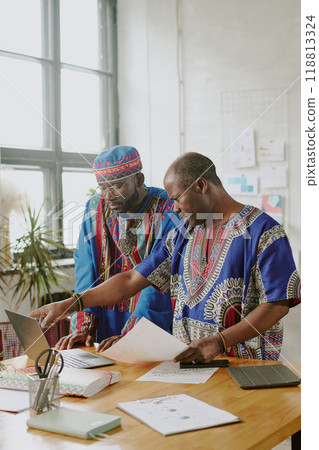 Vertical shot of African American teamlead helping his coworker with final project 118813324