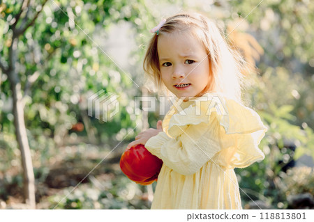 Cute child girl with a lush hairstyle in pastel dress in sunny garden. 118813801