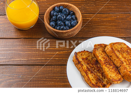 French toast on a white plate with blueberries and orange juice for breakfast French toast on a white plate with blueberries and orange juice for breakfast 118814697
