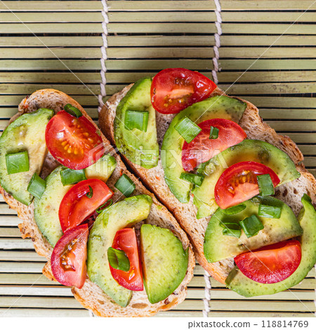 Avocado toast topped with tomato and green onion on a slice of carrot bread 118814769