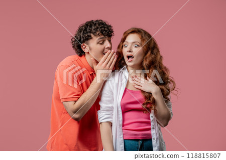 Gossiper man whispers in girlfriends ear secret, rumors, gossips, pink studio. Pretty lady and handsome guy, shh, conspiracy Gossiper man whispers in girlfriends ear secret, rumors, gossips, pink studio. Pretty lady and handsome guy, shh, conspiracy 118815807