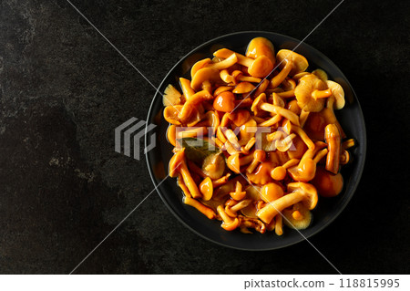 Homemade pickled honey mushrooms  on a black stone table. 118815995