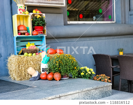 Halloween decorations. Decorated entrance of a house on the street. Pumpkins, flowers, spikelets, boxes as decorations 118816512
