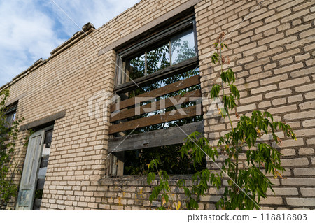 The window is boarded up. The window of an old, abandoned, brick store building The window is boarded up. The window of an old, abandoned, brick store building 118818803