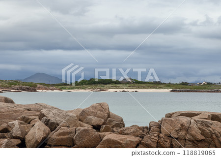 A view of Gurteen Beach in Ireland, framed by rugged rocks in the foreground 118819065