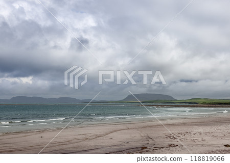 A tranquil view of Strandhill beach with gentle waves, distant hills along the coastline A tranquil view of Strandhill beach with gentle waves, distant hills along the coastline 118819066