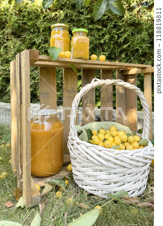 Rolled jars with jam under tree with apples. Harvest in garden. Small yellow apples for dessert, preparation for winter. Organic product.  118819811