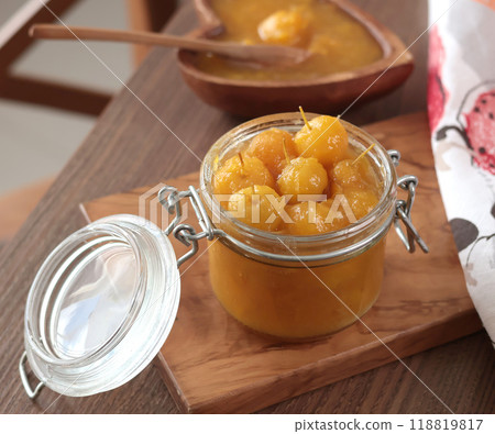 Glass jar of apple jam on wooden olive board. Home made fruit from garden. Kitchen interior and organic food.  118819817