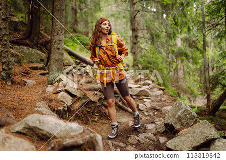 Traveler with yellow backpack walks along hiking path among mountains in the forest. Enjoys nature. 118819842