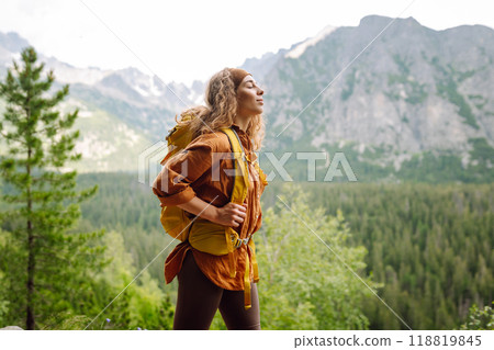 Happy woman with a yellow hiking backpack enjoying the mountain landscape. Travel concept. 118819845