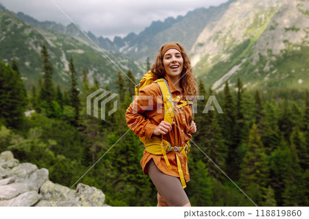 Happy woman with a yellow hiking backpack enjoying the mountain landscape. Travel concept. Happy woman with a yellow hiking backpack enjoying the mountain landscape. Travel concept. 118819860